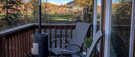Une terrasse en bois équipée d’un chauffage d’extérieur, de deux chaises et offrant une vue sur un paysage montagneux.