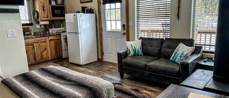 A compact living space with a kitchenette, a sofa, a bed, and a dining table.