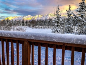 Un paysage de montagne enneigé, avec une terrasse en bois au premier plan.