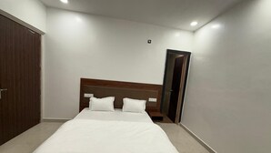 Een slaapkamer met een groot bed, een houten hoofdbord, een kledingkast en een spiegel aan de muur.