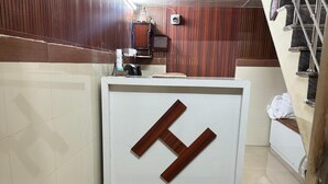 Een receptiebalie met een groot H-logo, een trap en een ventilator aan de muur.
