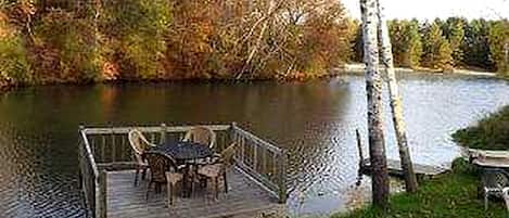 Un muelle de madera con una mesa y sillas junto a un lago.