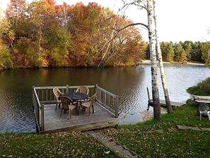 Un muelle de madera con una mesa y sillas junto a un lago.