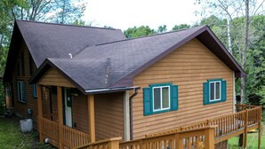 A wooden cabin with a porch, a covered deck, and a sloped roof. - Family-Friendly Cabin Rental on a Private Lake near Wisconsin Dells (Tomah)