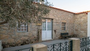 A stone building with a white door, a bench, and a sign that reads 'La Casa de la Luna.'