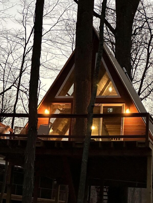Una cabaña con techo triangular, ventanas amplias y fachada de madera.