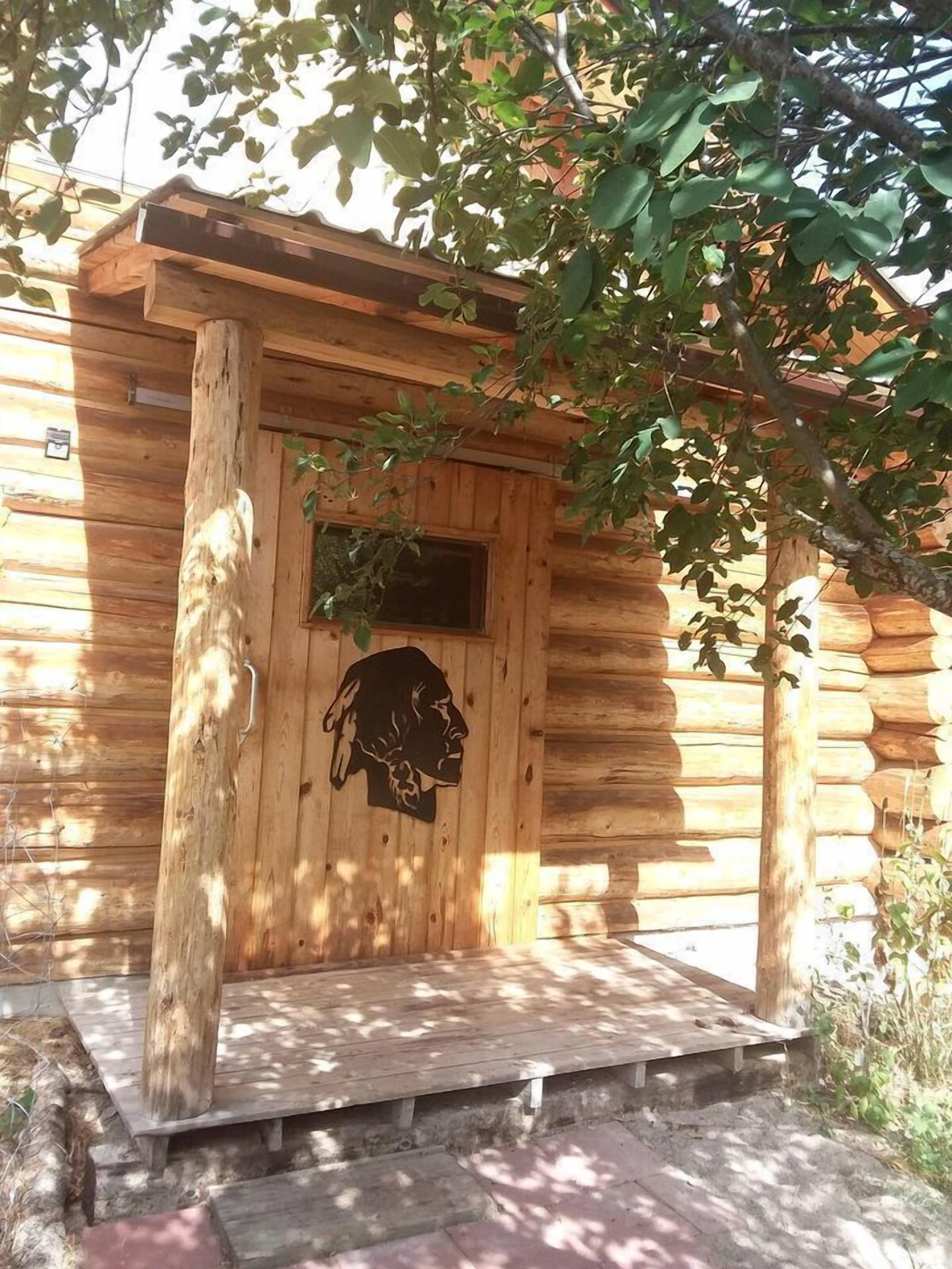Una cabaña de madera con un porche, una puerta tallada y una ventana.