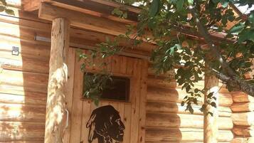 Una cabaña de madera con un porche, una puerta tallada y una ventana.