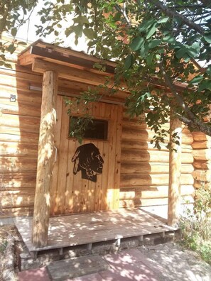 Une cabane en bois avec une véranda, une porte sculptée et une fenêtre.
