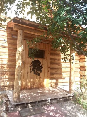 A wooden cabin with a porch, a carved door, and a window.