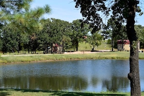 A calm lake with trees and a small building in the background.