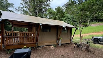 A rustic cabin with a covered porch, a small table with a black tablecloth, and a gravel area.