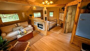 Ein gemütliches Blockhaus-Interieur mit Holzboden, einer Couch, einem Esstisch und einer Küchenzeile.