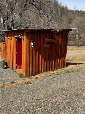 Une structure en bois avec une porte rouge, une enseigne indiquant « Bienvenue à Creekside », et un luminaire alimenté par énergie solaire.
