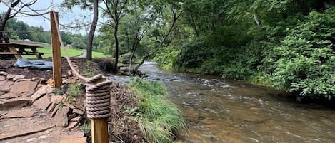 A natural outdoor setting with a stream, wooden steps, and a picnic table.
