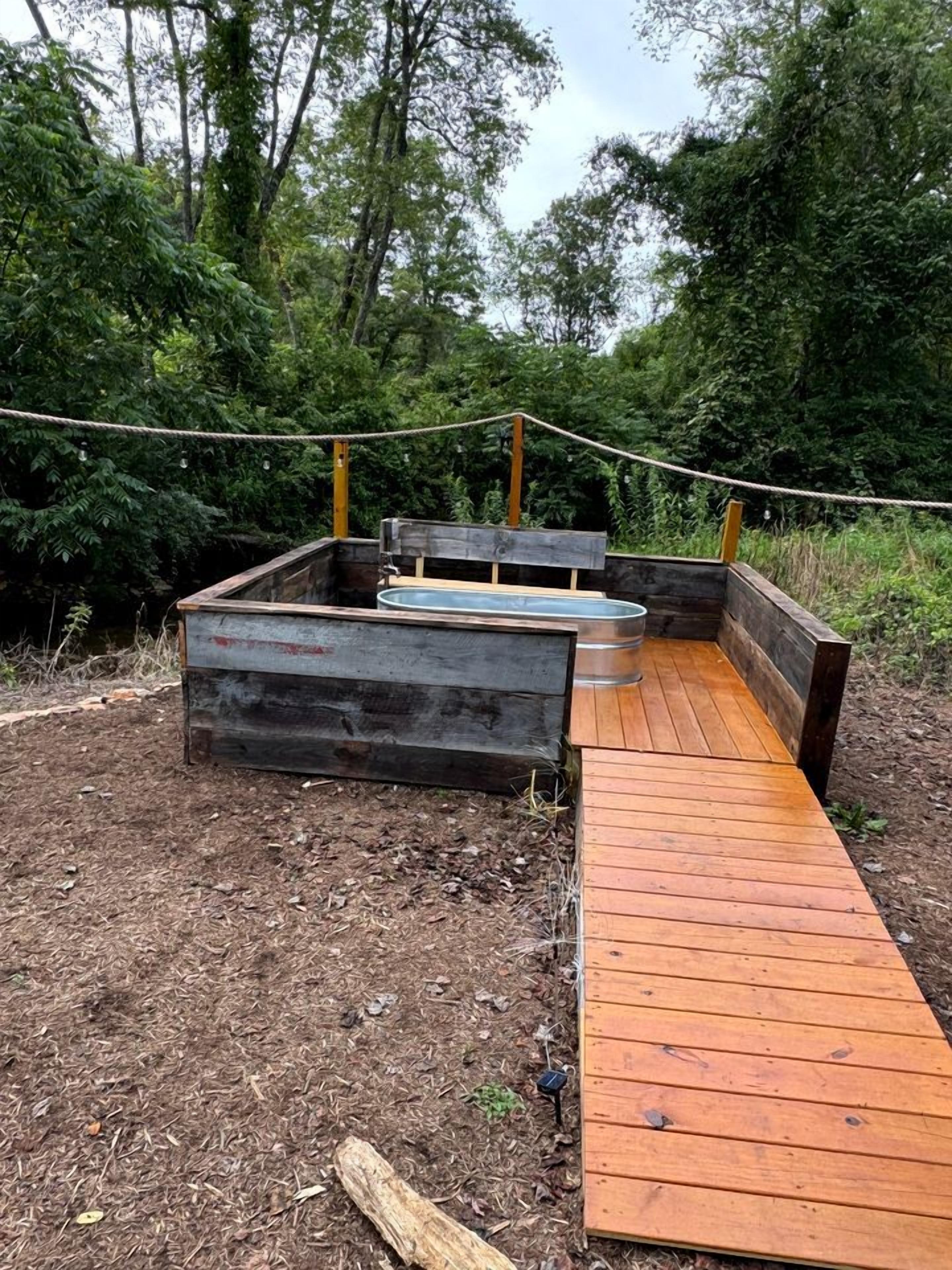 A wooden deck leading to a raised garden bed area with a metal container.