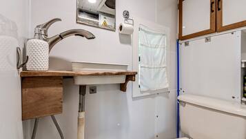 A bathroom with a sink, faucet, towel rack, and toilet.