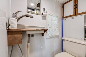 A bathroom with a sink, faucet, towel rack, and toilet.