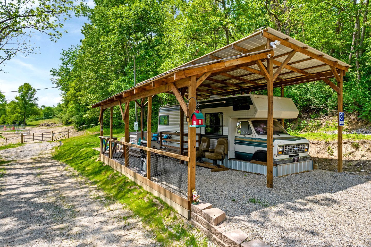 A covered RV park with a gravel path leading to a wooden structure.