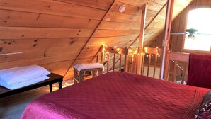 A wooden interior with a bed, a bench, and a window. - Romantic Log Cabin with Hot Tub near Cherokee National Forest, Tennessee (Coker Creek)