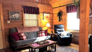 A cozy cabin interior with a sofa, armchair, and a coffee table. - Romantic Log Cabin with Hot Tub near Cherokee National Forest, Tennessee (Coker Creek)