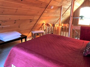A wooden interior with a bed, a bench, and a window. - Romantic Log Cabin with Hot Tub near Cherokee National Forest, Tennessee (Coker Creek)