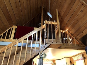 Una escalera de madera con un paño rojo, barandilla de madera y luces de cadena.