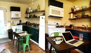 A compact kitchen with a microwave, stove, and sink. There is a laptop on a table and a chair.