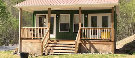 Une cabane dotée d’une véranda, d’un escalier en bois et d’un toit en métal.