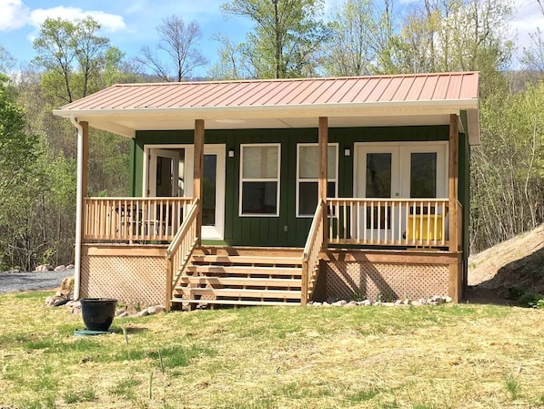 A cabin with a porch, wooden steps, and a metal roof.