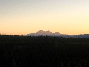 Vuoristoinen maisema, jossa etualalla on metsää ja taivaalla ei ole pilviä.