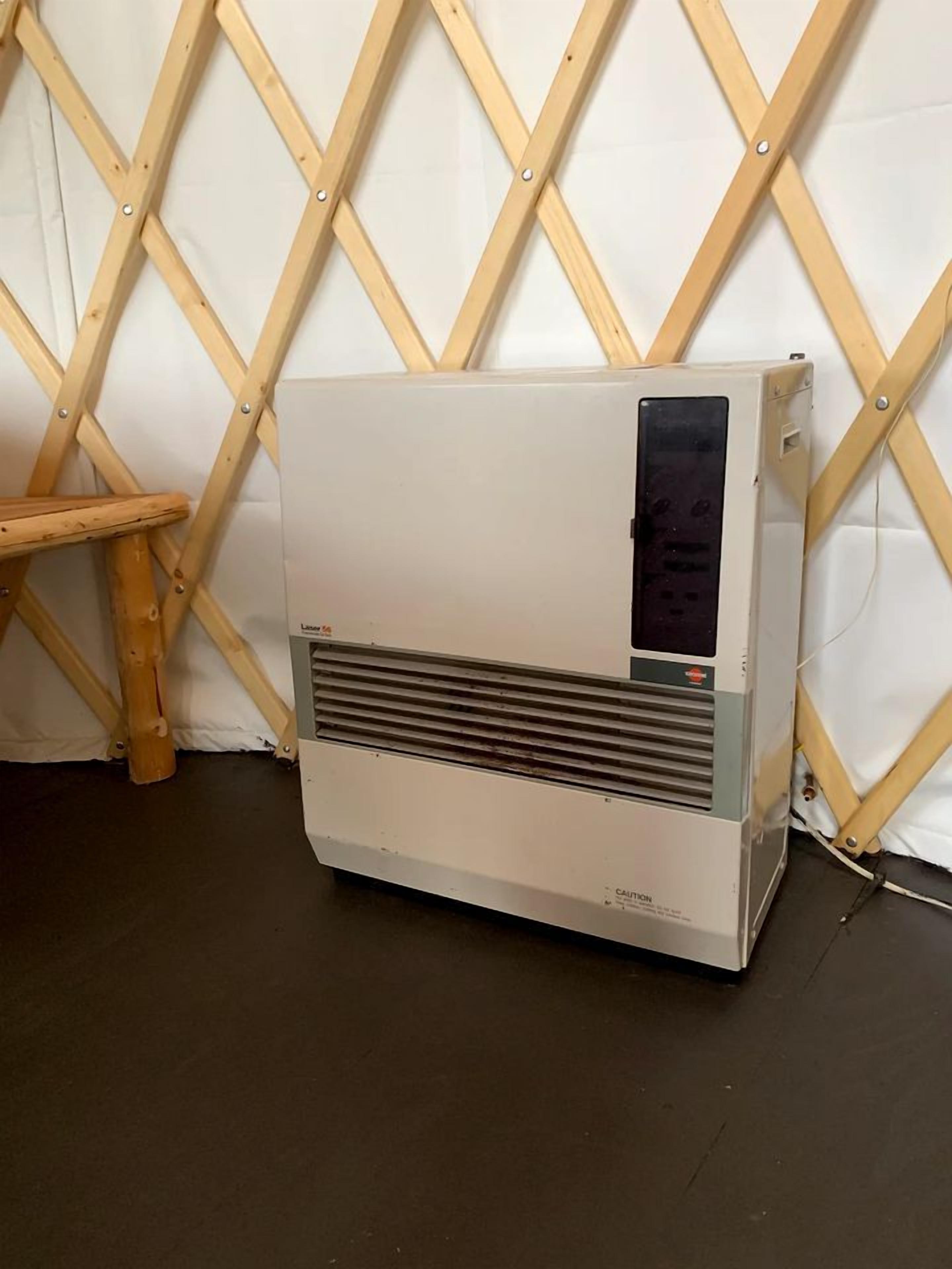 A portable air conditioner in a room with a wooden lattice wall and a wooden stool.