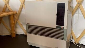 A portable air conditioner in a room with a wooden lattice wall and a wooden stool.