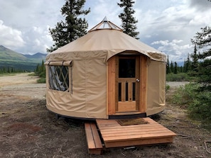 Una yurta con puerta de madera, un pequeño porche y una ventana.