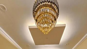 A hotel corridor with a chandelier, potted plants, and a clean, polished floor.