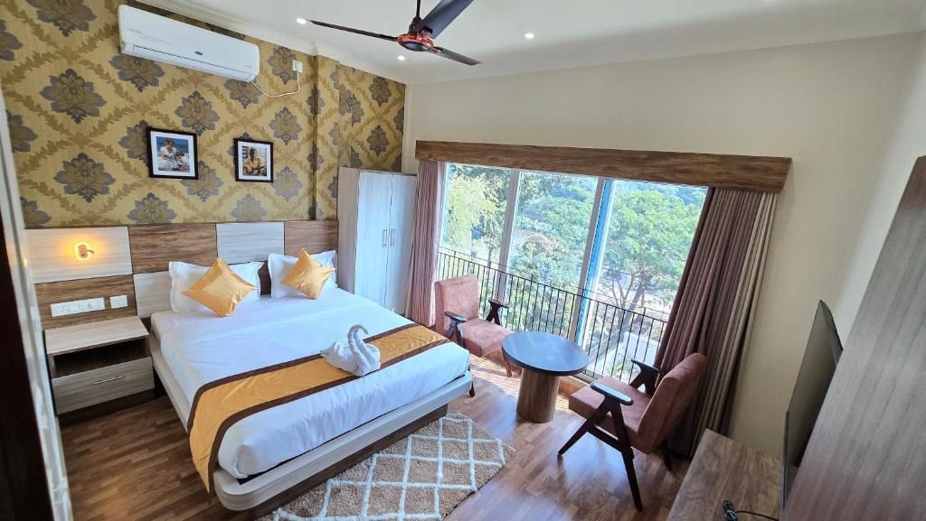 A hotel room with a large bed, a balcony with a table and chairs, and a ceiling fan.
