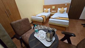 Una habitación de hotel con dos camas, una mesita con bandeja, una silla y un armario.