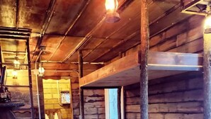 A rustic wooden cabin with bunk beds, a vintage stove, and a wooden floor.
