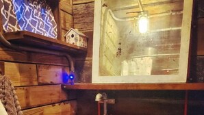 A rustic bathroom with a wooden barrel sink, a toilet, and a mirror above the sink.