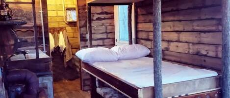 Un'accogliente baita di legno con letti a castello, una stufa d'epoca e un pavimento in legno.