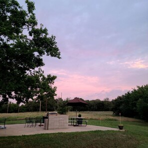An outdoor seating area with tables and chairs, a concrete block structure, and a gazebo.