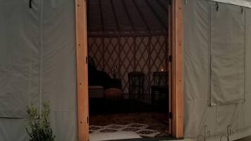 A large tent with a wooden door, a small porch, and a potted plant outside.