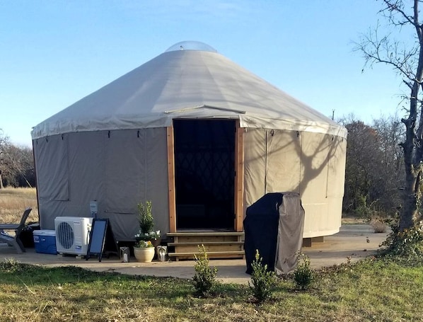 A yurt with a large entrance, a covered porch, and a small porch area with a bench.