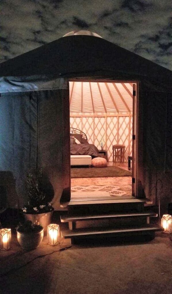 Una tienda de campaña con una cama, una mesita y una silla en su interior.