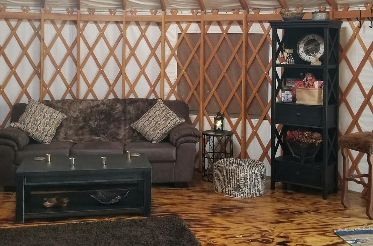 Een gezellige woonkamer met een bank, salontafel, poef en een boekenkast.