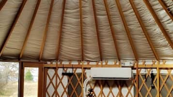 A tent with a ceiling fan, a Christmas tree, and a refrigerator.