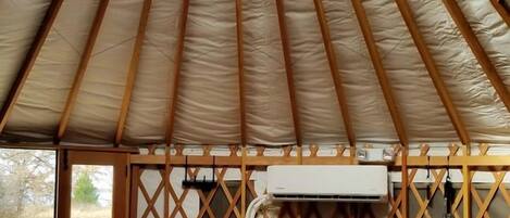 Une tente équipée d’un ventilateur de plafond, d’un sapin de Noël et d’un réfrigérateur.