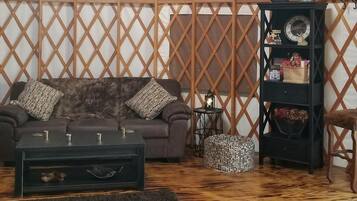 A cozy living room with a sofa, coffee table, ottoman, and a bookshelf.