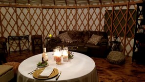 A round dining table with candles, plates, and cutlery set for a meal.