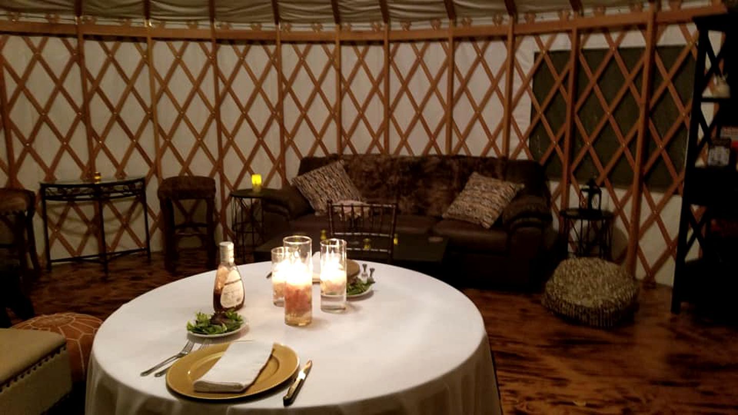 A round dining table with candles, plates, and cutlery set for a meal.